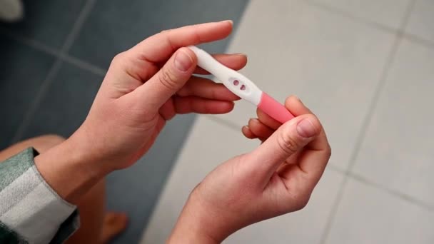 女性の手のオーバーヘッドクローズアップビュー ゆっくりと肯定的な結果を示すインクジェット妊娠検査を開催 妊娠検査中 ついに妊娠 — ストック動画