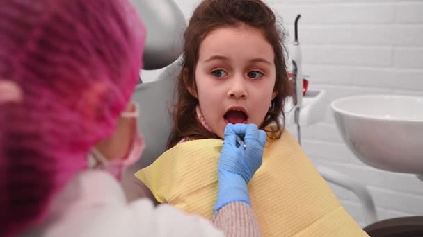 白人の5歳の美しい少女の閉鎖 歯科医の席に座って 小児胃科医による歯の検査を受けています 小児科 ストーモロジーだ 歯科診療 — ストック動画