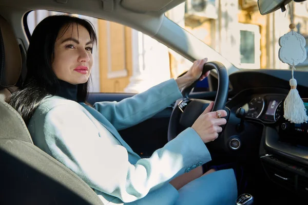 Portrait of happy female driver, beautiful confident middle-aged Caucasian woman, businesswoman, successful entrepreneur in casual wear, steering car with safety belt. People Lifestyle Driving concept