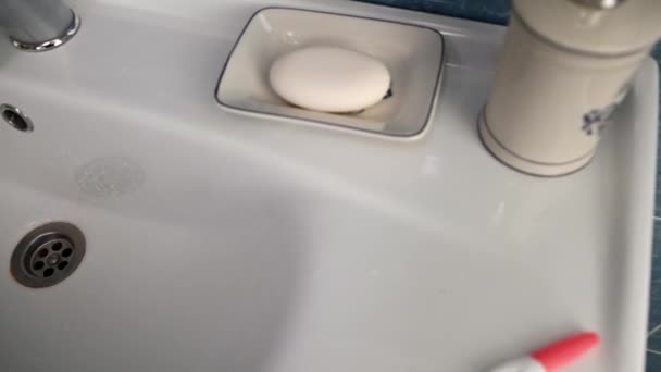 有选择地把重点放在家庭浴室的白色洗脸盆上的阳性妊娠测试上 从上面看旋转弹丸 — 图库视频影像