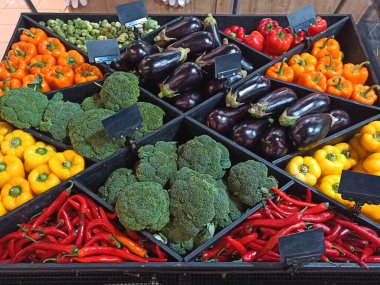 Assortment of fresh organic vegetables on the counter of a grocery supermarket for healthy lifestyle: broccoli, eggplants, chili pepper, colorful peppers. Top view. Veganism and healthy eating concept