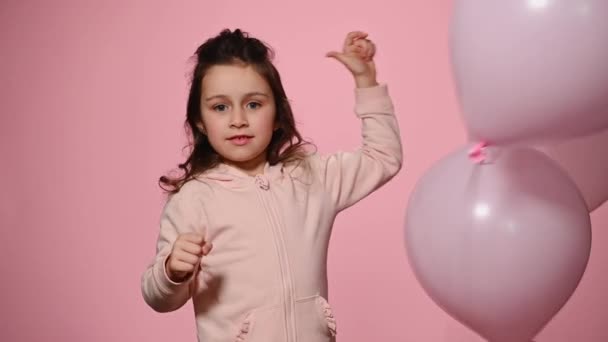 かわいい白人5歳の子供 素敵な赤ちゃんの女の子は インフレータブルヘリウムピンクのパステル風船で遊んでいます カメラを見て美しいおもちゃの笑顔を笑顔 ピンクの色の背景に孤立 — ストック動画