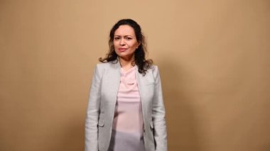 Indignant shocked woman, asking What looking at camera, crossing hands over chest, staring with displeasure, taking deep breath while expressing bewilderment, on isolated beige background