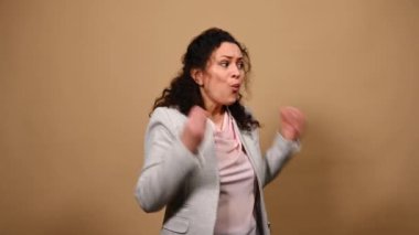 Furious stressed worried middle-aged woman looking to the sides, asking what, touching her head while feeling stress and headache, screaming on isolated beige background. People. Emotions