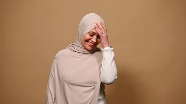 陽気中東イスラム教徒女性身に着けていますベージュヒジャーブ 親指を表示アップカメラを見て ポーズ彼女の目で閉じクリーム隔離された背景 — ストック動画