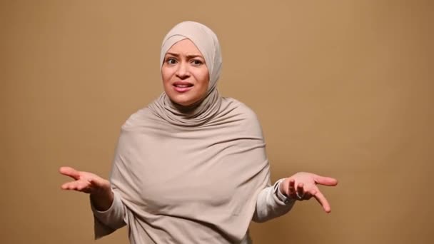 穆斯林妇女头戴米黄色头巾 表示失望和误解 问什么 看着相机 指着自己 表示否认和拒绝 因米黄色背景而被孤立 — 图库视频影像
