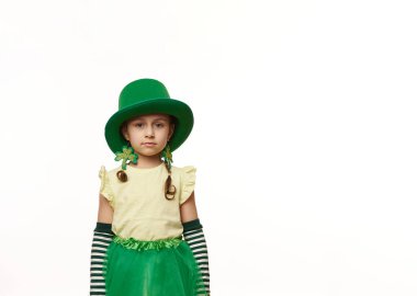 Leprechaun karnaval kostümü ve yonca yaprağı küpeleri takmış beyaz arka planda izole edilmiş kameraya bakan iki komik at kuyruklu sevimli İrlandalı kız çocuğu. Aziz Patrick Günü konsepti