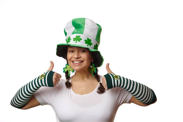迷人的女人 戴着绿色和白色条纹手套 头戴带有三叶草叶的妖精帽 微笑着 竖起大拇指看着相机 与白色背景隔离 圣帕特里克节 — 图库照片