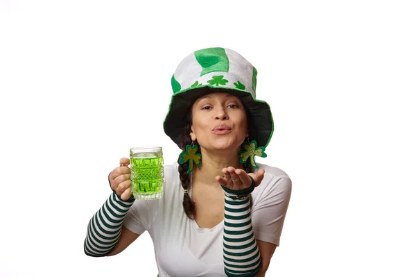 穿着狂欢节服装的年轻貌美的女人 拿着一大杯绿色啤酒 在镜头前吹出一个空气之吻 与白色背景隔离 爱尔兰文化和传统 — 图库照片