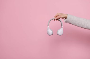 Fotokopi reklam alanı olan kablosuz kulaklıkları kapalı bir arka plan üzerinde tutan eller. Müzik endüstrisi. - İnsanlar. Eğlence