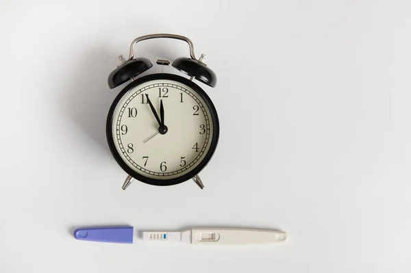 Επίπεδη Θέσει Μαύρο Ρετρό Ξυπνητήρι Και Κιτ Δοκιμών Εγκυμοσύνης Δείχνει — Φωτογραφία Αρχείου
