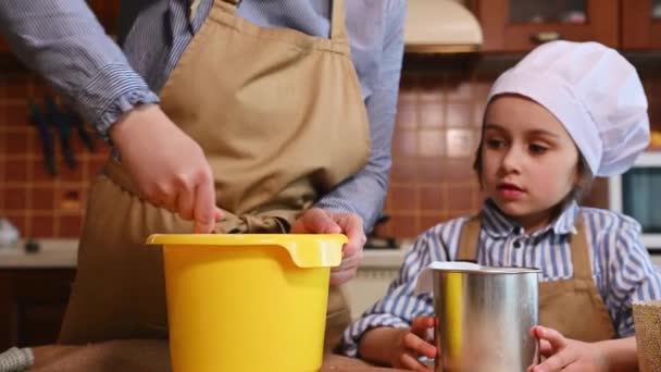 選択的フォーカス 彼女の小さな驚きの娘は料理のプロセスを見ている間 レーズンで生地を準備クローズアップ女性 幸福と驚きを表現 家庭用キッチンでイースターケーキを準備 — ストック動画