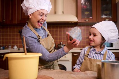 Mutlu, neşeli bir aile, sevgi dolu bir anne ve tatlı küçük bir kız birlikte eğleniyor, Paskalya pastası, hamur işleri ve panettone pişirirken mutfakta şenlik havasının tadını çıkarıyor. - İnsanlar. Yaşam tarzları. Boş vakitler