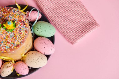 Paskalya ortodoks tatlı ekmeği ve açık pembe pastel arka planda renkli yumurtalar. Paskalya bayramlarında kahvaltı konsepti. Reklam alanını kopyala. Panettone Rus Kulich Paskalya pastası. Üst görünüm