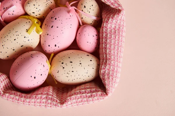 Cropped view of Easter eggs of pink and beige colors in red checkered napkin, isolated cream background. Happy Easter. Celebrating religious event, symbol of resurrection of Jesus Christ. Copy space