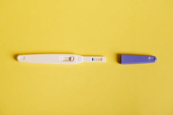 stock image Rapid diagnosis of pregnancy at home. Top view of inkjet pregnancy test kits with a biochemical reaction between hCG and urine appearing in two bars, isolated on yellow background. Copy ad space