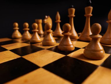 Satranç oyunu. Beyaz piyonlar ve satranç taşları satranç tahtasının üzerinde, siyah arka planda izole edilmiş. Rekabet, savaş, liderlik gelişimi, iş stratejisi ve riskler kavramı