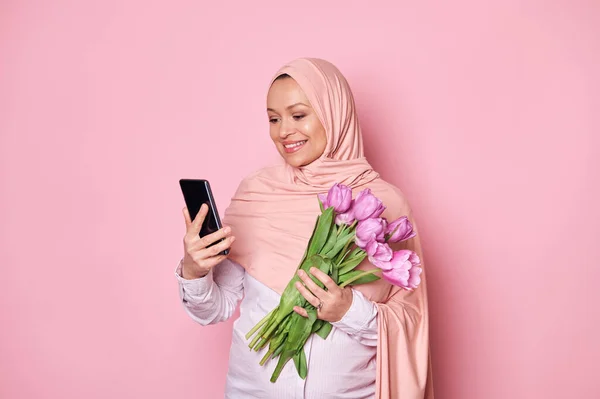 Арабська Мусульманка Вагітна Рожевому Хіджабі Тримає Букет Пурпурових Тюльпанів Перевіряє — стокове фото