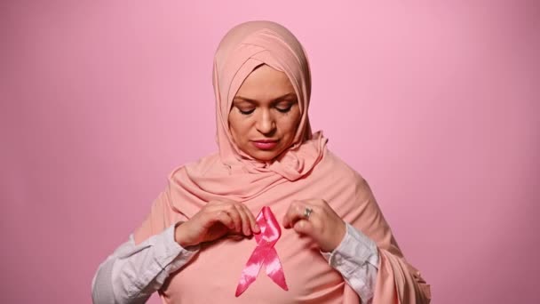 穿着头巾的穆斯林妇女 穿着粉色缎带 象征着世界癌症意识日 孤立的背景 支持乳腺癌运动 十月一日品红月的概念与女性健康 — 图库视频影像