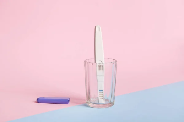 Still life. Inkjet pregnancy test with two bars, showing positive reaction between female urine and chg hormone, isolated bicolor pink and blue background. Womens health and Planning maternity