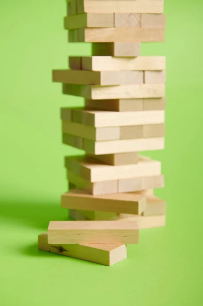 Wooden blocks on green background. Board games developing fine motor skills. Removing wooden blocks from the tower. Entertainment activities. Construction and building concept