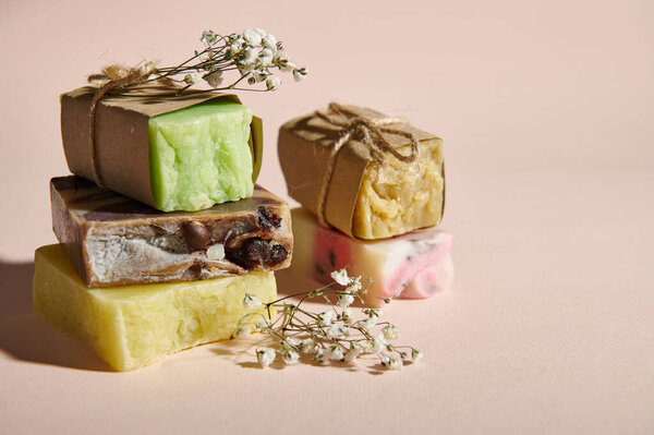 Still life. Bars of organic soap wrapped in eco paper and gypsophila flowers, on isolated beige background. Concept of natural ecological cosmetic products for skin body care with natural ingredients