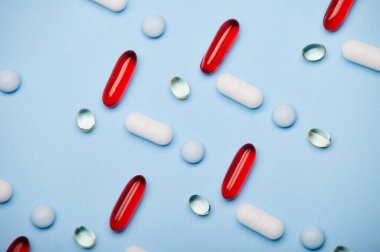 Düz yatıyordu. Tıbbi ilaçların geçmişi, kırmızı yarı şeffaf jel kapsülleri ve izole edilmiş mavi arka planda desenler oluşturulmuş. Antidepresan tedavisi. Ağrı kesici. İlaç işi ve endüstri konsepti