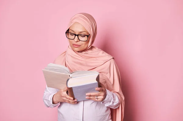 ピンクのヒジャーブと流行のメガネで中東のイスラム教徒の女性を確信し 孤立した色の背景に関する本を読んでください 教育を受けた人々の概念 イスラム教 エデュレーション 女性の権利 社会問題 — ストック写真