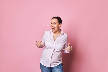 Aşırı neşeli, heyecanlı, mutlu, ağırbaşlı kadın, pozitif duygularını ifade eden, kameraya gülümseyen, hamile karnını işaret eden, pembe arka planda soyutlanmış. Uzayı kopyala Anneler Günün kutlu olsun. Annelik kavramı