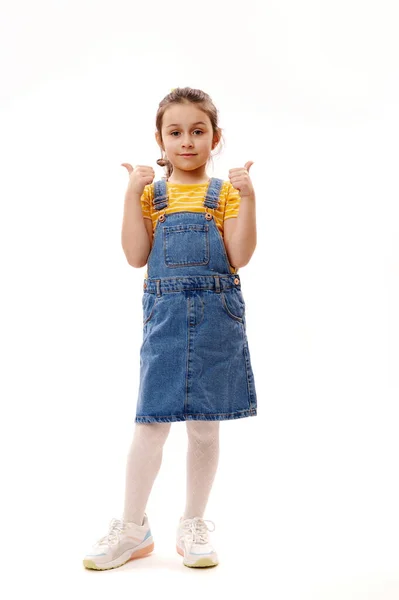 Pełnowymiarowy Portret Białej Dziewczynki Dżinsowych Ciuchach Patrzącej Kamerę Gestykulującej Kciukami — Zdjęcie stockowe