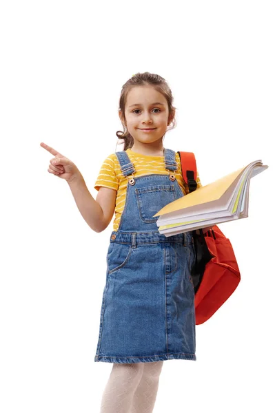 肯定的なスマート女子高生は 1年生の教科書を保持し 孤立した白い背景にコピー広告スペースを指して カメラを見て笑顔 新しい学期へようこそ 学校に戻る — ストック写真