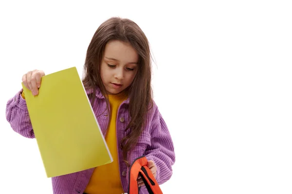 クローズアップポートレート 愛らしい小学生 かわいい赤ちゃんの女の子は 白い背景に隔離されたオレンジ色のバックパックに教科書を入れます コピースペース 新学期の学校に戻る — ストック写真