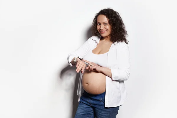 Gravid Middelaldrende Kvinne Sjekker Tiden Armbåndsuret Sitt Teller Babybevegelser Smiler – stockfoto