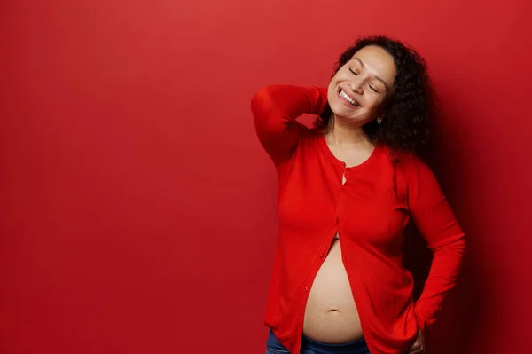中年の自信を持って美しい妊婦の本物のスタジオの肖像画 裸の腹と閉じた目をポーズ妊婦 孤立した赤い色の背景に笑みを浮かべて 妊娠中 — ストック写真