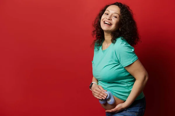 Mujer Embarazada Encantadora Riendo Mirando Cámara Sosteniendo Botines Bebé Sobre — Foto de Stock
