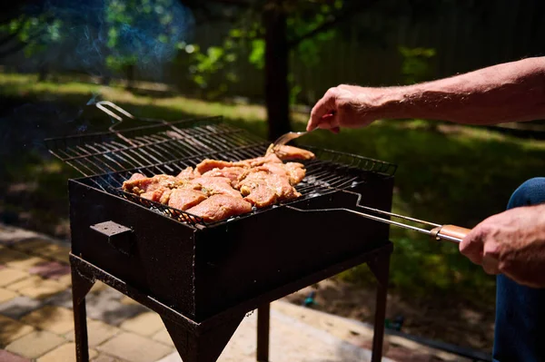 密接男性の手は裏庭のバーベキューグリルで肉を調理しながら フォークでマリネステーキをピアス 食べ物の背景 食料の準備だ 選択的フォーカス 週末のレジャー — ストック写真