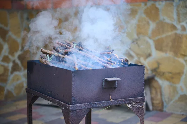 在后院的一个黑色烤架上 燃烧着树枝的烤肉火中冒出的浓烟的特写镜头 在露天准备食物 夏天出去放松和户外野餐的概念 — 图库照片