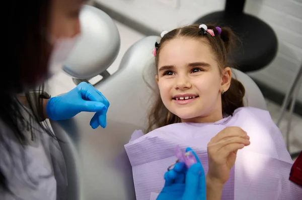 歯科医の椅子に座っている多民族の小さな子供の女の子は 歯科クリニックの小児科で定期的な歯科検査中に医師の歯科衛生士に大きく笑顔を見せます 小児科 小児歯治療 — ストック写真