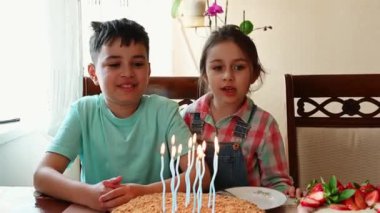 Yakışıklı İspanyol ergen çocuk doğum günü partisini kutluyor. Tatlı küçük kız kardeşi doğum günü şarkısını söylerken lezzetli pastasının üzerine mum üflüyor. Çocukluk. Şenlikli yaşam etkinliği