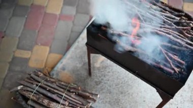 Arka bahçedeki barbekü ızgarasının üzerinde yanan ağaç dalları olan sıcak bir barbekü ateşinden gelen dumanın görüntüsü. Açık havada yemek hazırlıyorum. Yaz rahatlama ve piknik konsepti