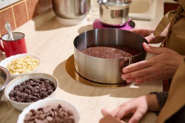Yakın plan fırıncı çikolatalı bisküviyi çıkarılabilir metal pasta kalıbının içine yerleştiriyor ve mutfak tezgahında lezzetli yemek malzemeleriyle duruyor. Fırın. Şekerleme. Mutfak konsepti