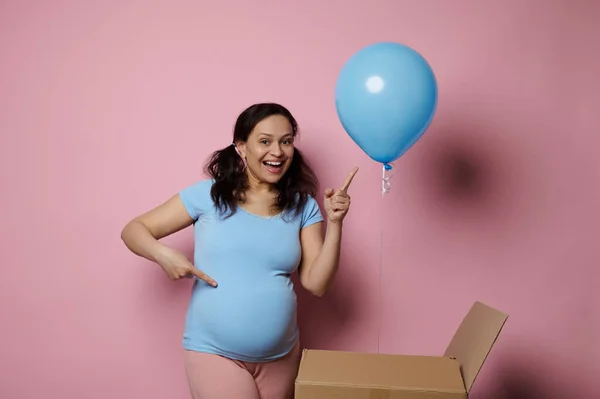 期待される将来のお母さん 妊娠中の女性が笑顔と青い風船で指を指して 彼女はピンクの背景に隔離された赤ちゃんの男の子を期待しています ジェンダーは政党の概念を明らかにする 妊娠中 出産だ — ストック写真