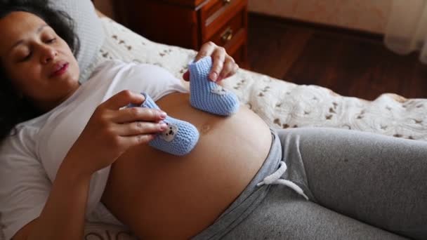 Top View Pregnant Woman Putting Baby Booties Her Belly Late — Αρχείο Βίντεο
