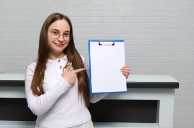 Hastanedeki ya da klinikteki resepsiyondaki hoş bayan resepsiyonist, kameraya beyaz boş kağıt levha ve bedava reklam alanı gösteriyor. Model