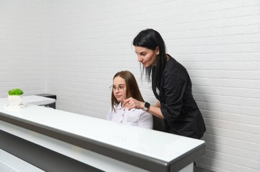 Modern poliklinikte, klinikte ya da güzellik salonunda tıbbi personel resepsiyonda konuşuyor. Şık siyah üniformalı kadın doktor diş hekimliği kliniğinin yöneticisiyle konuşuyor.