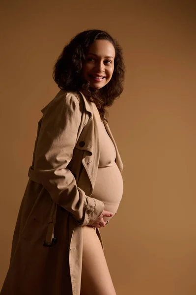 穿着米色内衣裤 穿着时髦风衣 手挽手 面带微笑的准妈妈的时尚美的画像 美丽的怀孕观念 — 图库照片