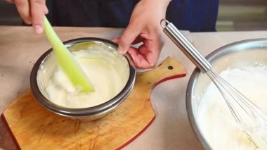 Bir hamur işi şefinin elleri erimiş beyaz çikolatayı metal bir kasede kremayla karıştırıyor, mutfak tezgahında taze organik malzemelerle duruyor. Mutfak ve şekerleme konsepti