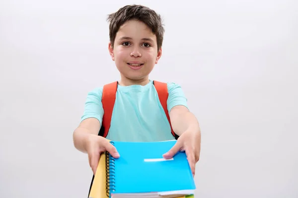 聪明的男孩笑容满面 背着橙色的背包 拿着彩色课本和学习用品 在白色的工作室背景下与世隔绝 复制广告空间 回学校去 — 图库照片