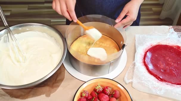 トップビューペストリーシェフ キッチンスプーンを使用してお菓子は 酢酸境界膜と取り外し可能な金属ケーキ金型内のスポンジケーキの上にホイップクリームやカスタードを置きます ムースデザートの準備の段階 — ストック動画