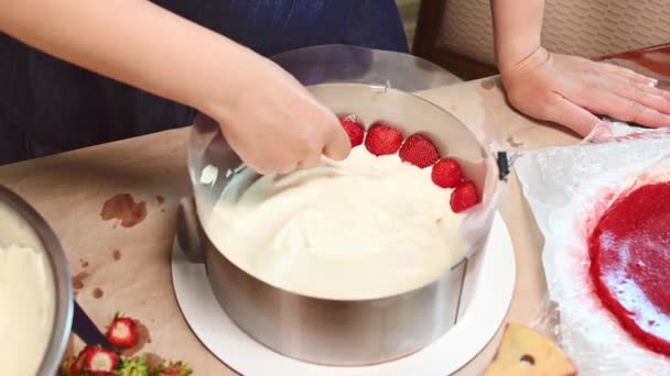フランスの甘い夏のデザート フライザームースケーキ ビスケットとストロベリーケーキ ムースとゼリー ケーキの上に新鮮な有機イチゴの半分を置く主婦のクローズアップビュー — ストック動画